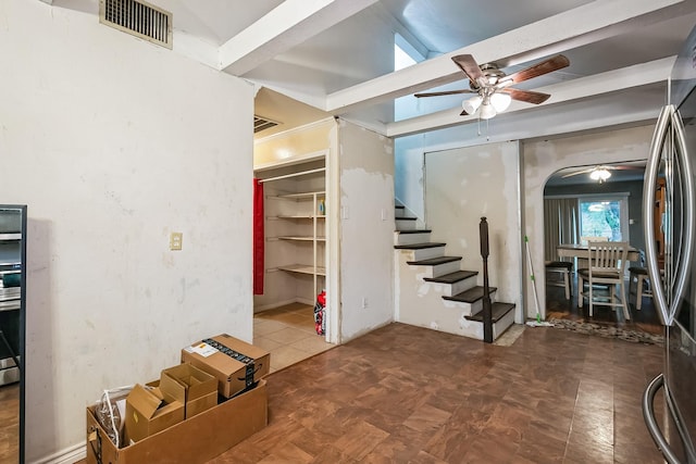 basement with ceiling fan and stainless steel fridge