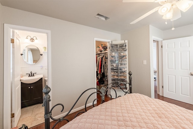 bedroom with connected bathroom, ceiling fan, sink, a walk in closet, and a closet