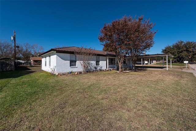 rear view of house featuring a lawn and a carport