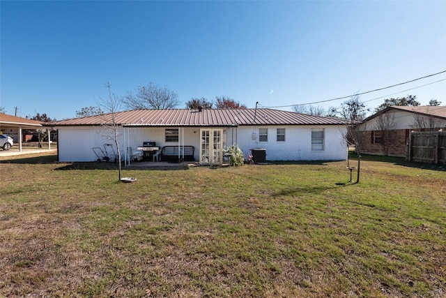 rear view of property featuring central air condition unit and a lawn