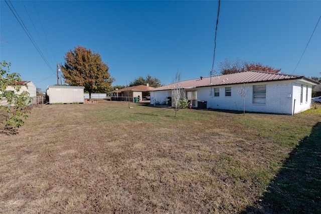 back of house with a lawn and a storage unit