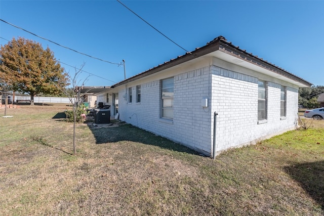 view of side of property with a lawn and central AC unit