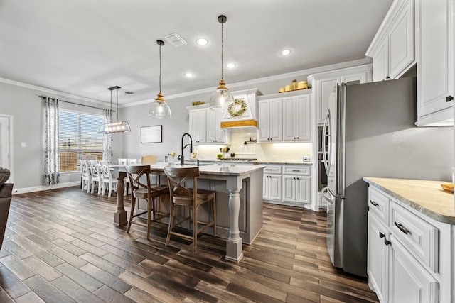 kitchen with dark wood-style floors, a breakfast bar area, freestanding refrigerator, and ornamental molding