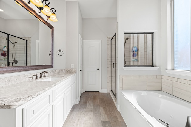 full bathroom with vanity, wood finished floors, baseboards, a shower stall, and a garden tub