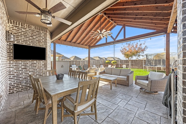 view of patio featuring outdoor dining space, an outdoor living space, a trampoline, a fenced backyard, and ceiling fan