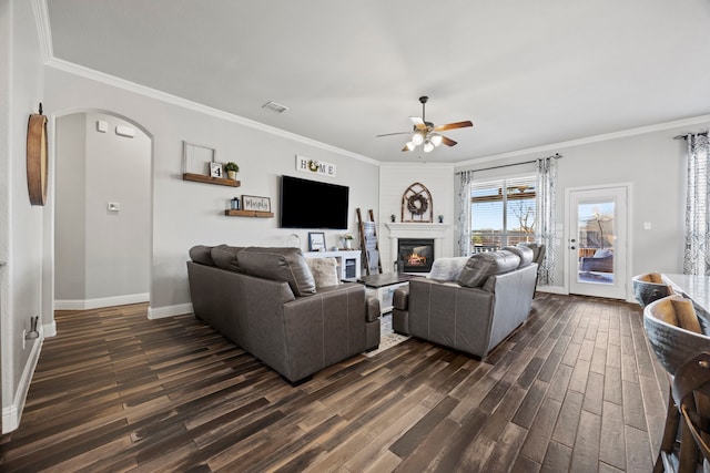 living room with visible vents, arched walkways, a glass covered fireplace, a ceiling fan, and dark wood-style flooring