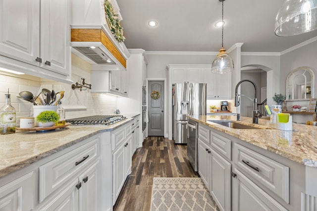 kitchen featuring ornamental molding, stainless steel appliances, arched walkways, white cabinetry, and a sink