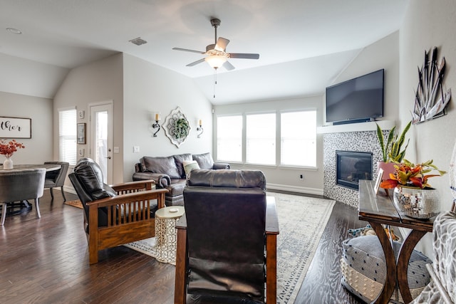 living room with dark hardwood / wood-style flooring, plenty of natural light, lofted ceiling, and a tiled fireplace