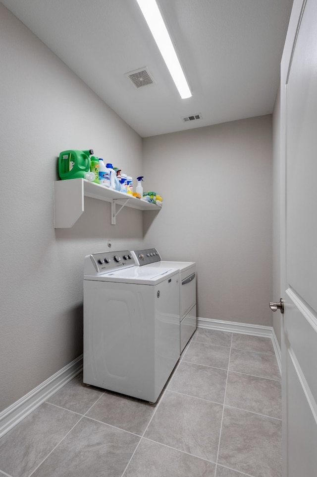 laundry area featuring washing machine and clothes dryer and light tile patterned floors