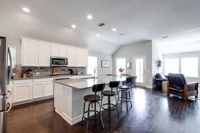 kitchen featuring a center island with sink, white cabinetry, stainless steel appliances, and dark wood-type flooring