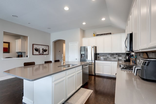 kitchen featuring dark hardwood / wood-style flooring, stainless steel appliances, a center island with sink, white cabinets, and lofted ceiling