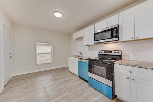 kitchen with appliances with stainless steel finishes, light hardwood / wood-style flooring, white cabinetry, and light stone counters