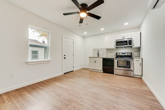 kitchen with stainless steel appliances, light hardwood / wood-style flooring, an AC wall unit, backsplash, and white cabinets