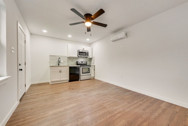 kitchen featuring ceiling fan, stainless steel appliances, an AC wall unit, white cabinets, and light wood-type flooring