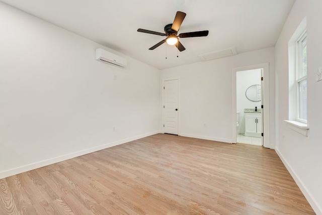 empty room featuring a wall unit AC, ceiling fan, and light hardwood / wood-style floors