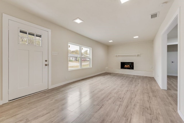 2233 Eastover Ave, Fort Worth, TX 76105 - unfurnished living room featuring healthy amount of natural light, light wood-style flooring, and a brick fireplace