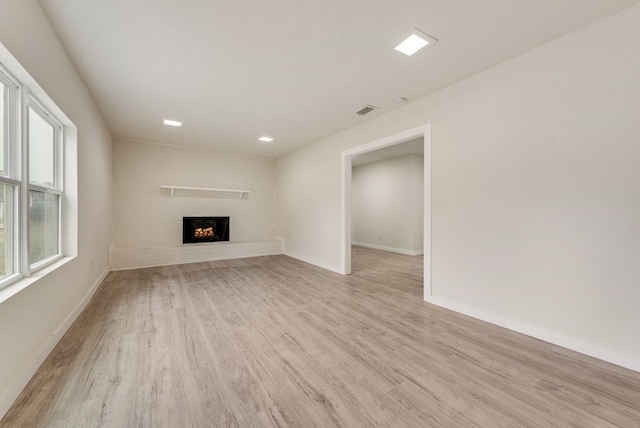 2233 Eastover Ave, Fort Worth, TX 76105 - unfurnished living room with light wood-style flooring and a lit fireplace