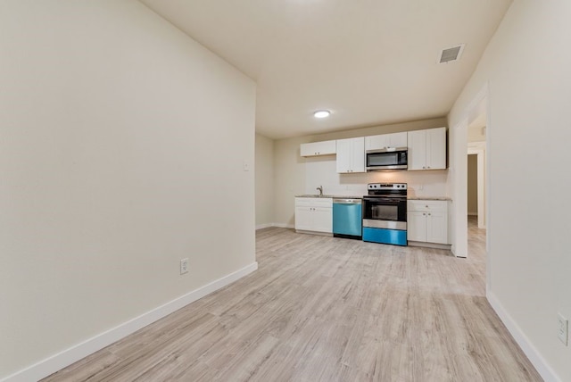 kitchen with white cabinets, appliances with stainless steel finishes, and light wood-type flooring