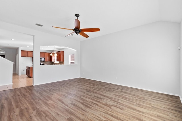 unfurnished living room featuring ceiling fan, lofted ceiling, and light wood-type flooring