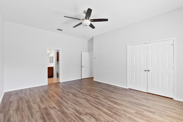 unfurnished bedroom with a closet, ceiling fan, ensuite bath, and light hardwood / wood-style flooring