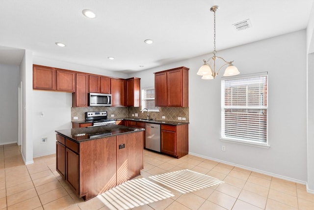 kitchen featuring sink, hanging light fixtures, stainless steel appliances, a kitchen island, and decorative backsplash