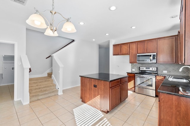 kitchen with appliances with stainless steel finishes, decorative light fixtures, sink, a center island, and light tile patterned floors