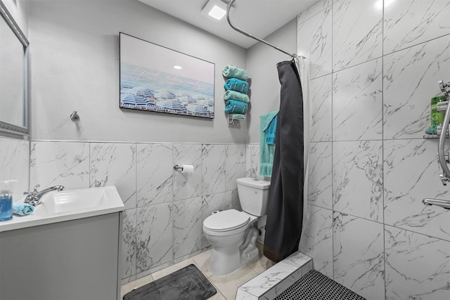 bathroom with curtained shower, tile patterned flooring, toilet, vanity, and tile walls