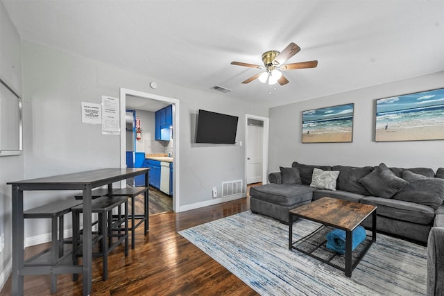 living room featuring ceiling fan and dark wood-type flooring