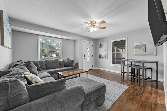 living room featuring dark hardwood / wood-style floors, ceiling fan, and a textured ceiling