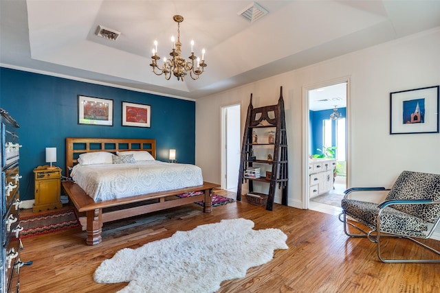 bedroom with wood-type flooring, a notable chandelier, and a tray ceiling