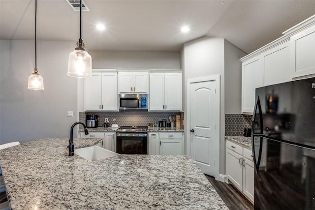 kitchen featuring white cabinets, decorative light fixtures, stainless steel appliances, and sink