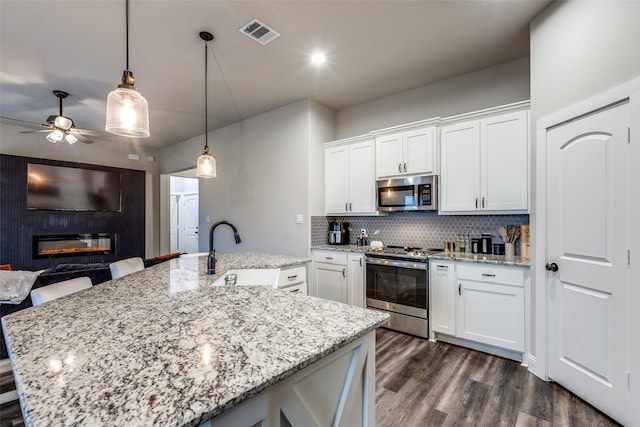 kitchen with white cabinets, sink, ceiling fan, an island with sink, and stainless steel appliances