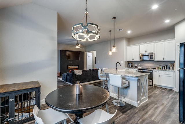 dining area with ceiling fan with notable chandelier, dark hardwood / wood-style floors, and sink