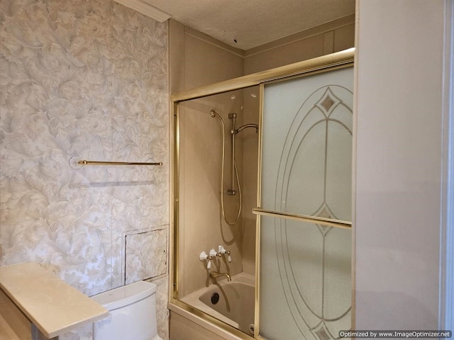 bathroom with combined bath / shower with glass door, a textured ceiling, and toilet