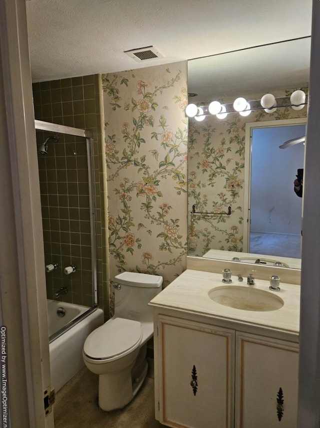 full bathroom with vanity, a textured ceiling, toilet, and bath / shower combo with glass door