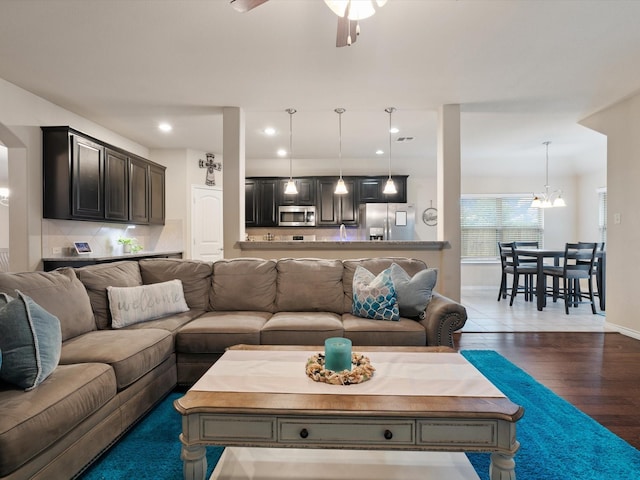 living room with dark hardwood / wood-style floors and ceiling fan with notable chandelier