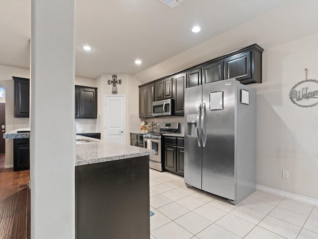 kitchen featuring tasteful backsplash, light stone countertops, light tile patterned flooring, and stainless steel appliances