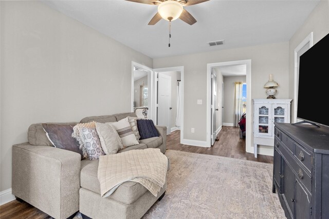 living room featuring ceiling fan and dark wood-type flooring