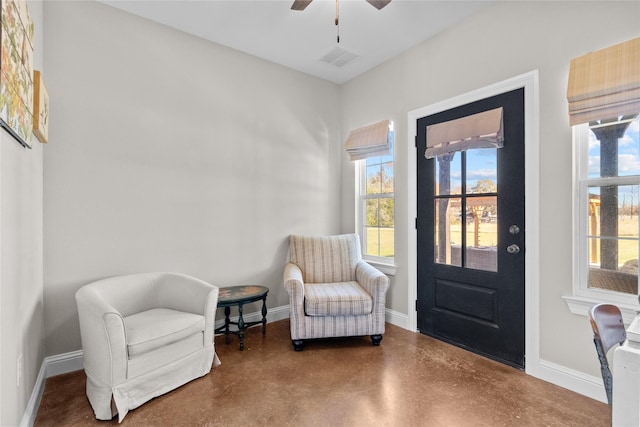 living area with ceiling fan and concrete floors