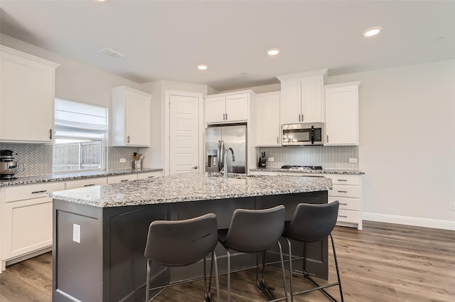 kitchen featuring white cabinets, dark hardwood / wood-style floors, an island with sink, and appliances with stainless steel finishes