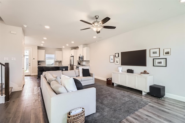 living room featuring dark wood-type flooring, sink, and ceiling fan