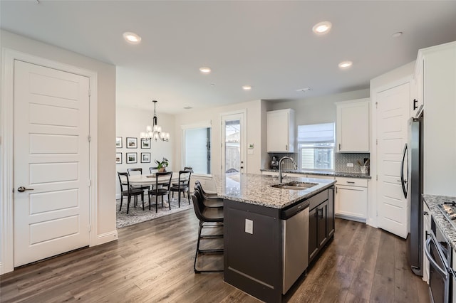 kitchen featuring appliances with stainless steel finishes, dark hardwood / wood-style flooring, sink, white cabinetry, and an island with sink