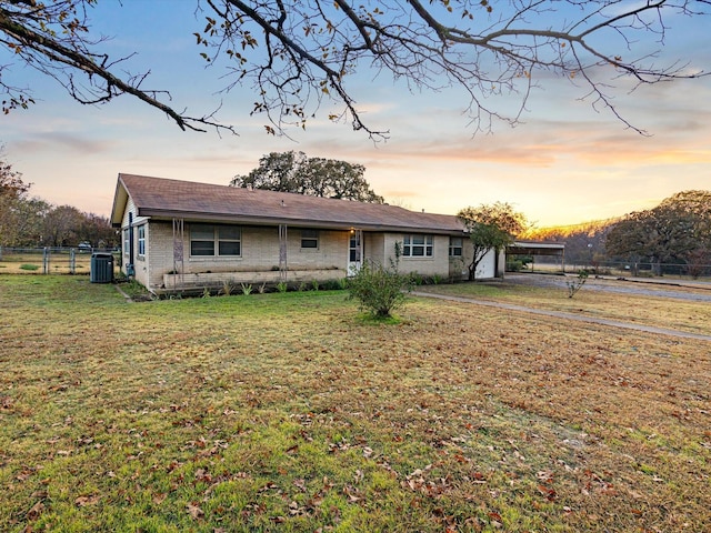 single story home with central air condition unit and a lawn