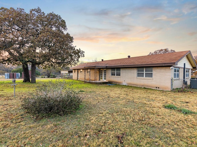 back house at dusk with a yard and central AC