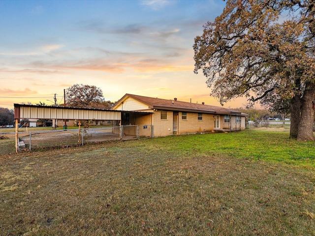 back house at dusk with a yard and a carport