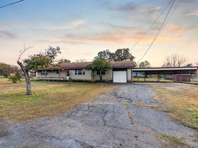 single story home featuring a lawn, a carport, and a garage