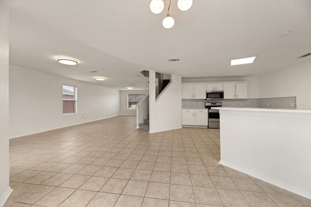 kitchen featuring decorative light fixtures, white cabinets, stainless steel appliances, and light tile patterned floors