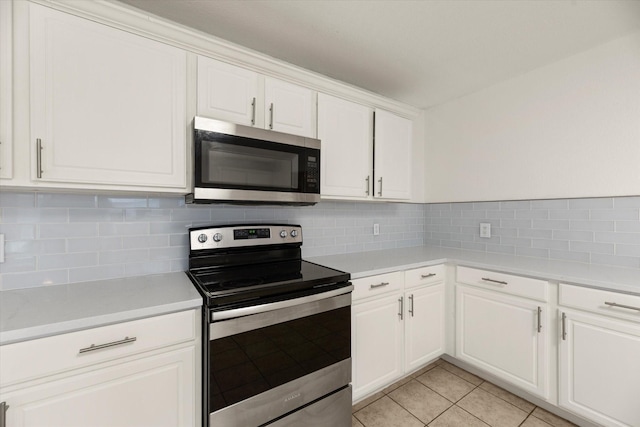 kitchen featuring white cabinets, light tile patterned floors, backsplash, and appliances with stainless steel finishes