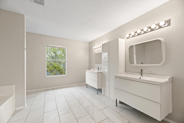 bathroom with a tub, vanity, and a textured ceiling