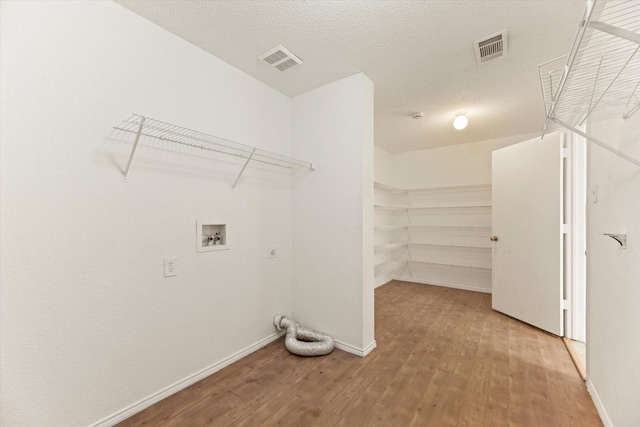 clothes washing area with hardwood / wood-style floors, hookup for an electric dryer, a textured ceiling, and washer hookup